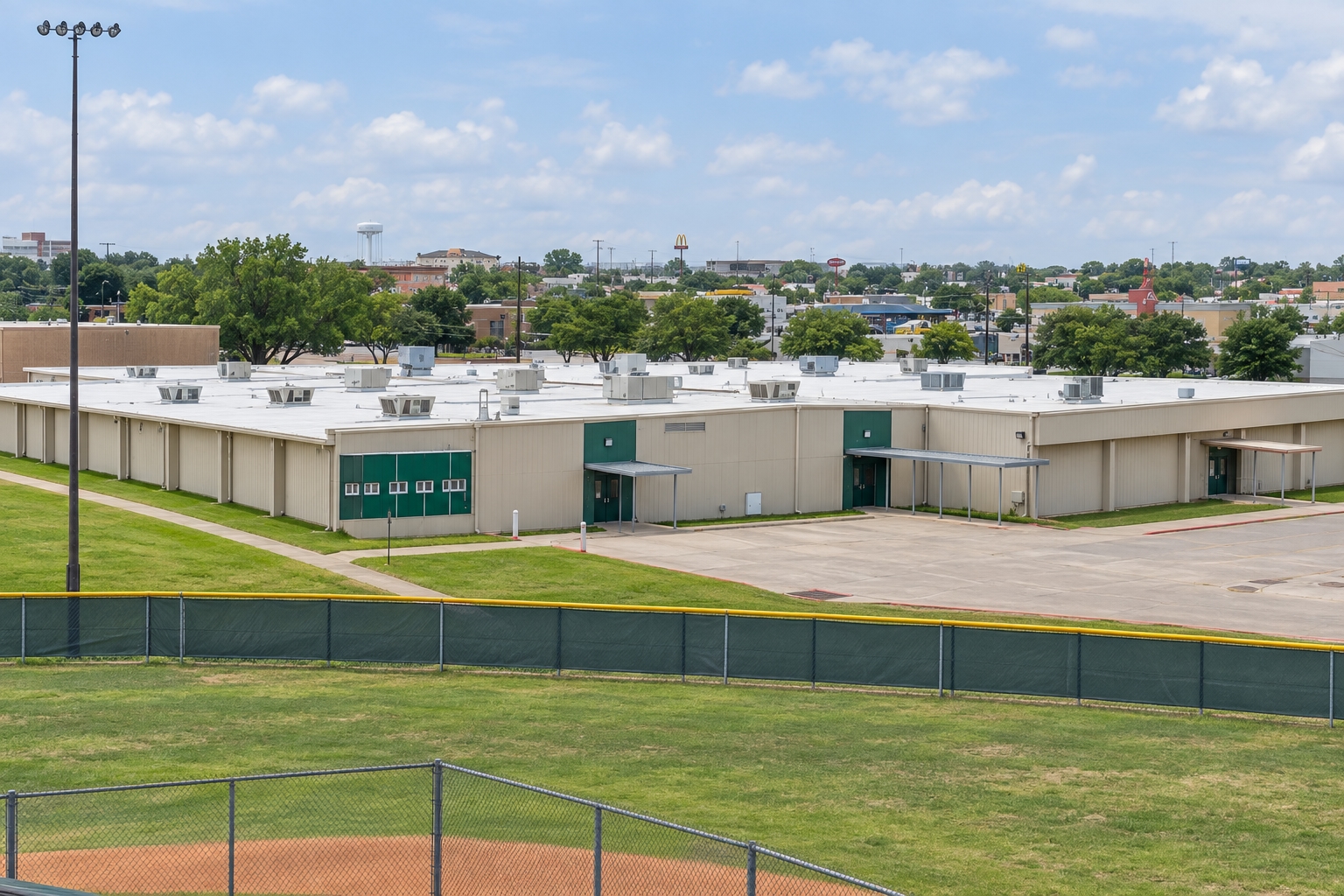 Campus illustration of Waxahachie High School of Choice’s low campus buildings beside the athletic grounds